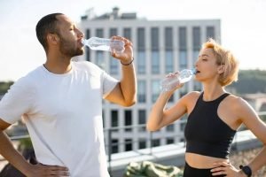 Imagem ilustrativa de um homem e uma mulher bebendo água em uma garraga / IStock