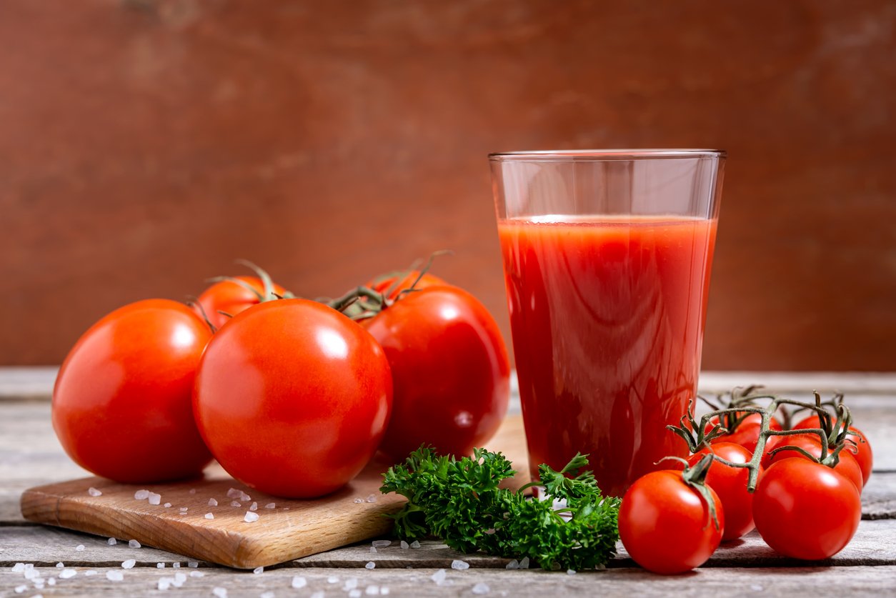 Imagem ilustrativa de tomates e um copo de molho de tomate