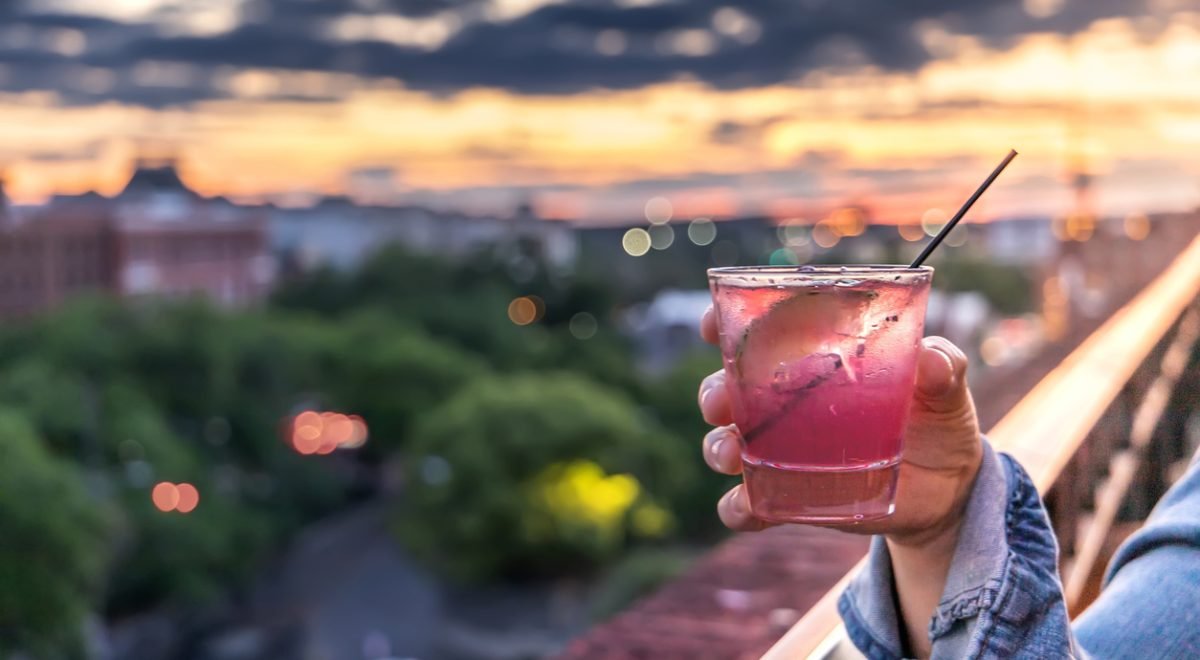 IStock/ucpage - Imagem ilustrativa de um drink e paisagem ao fundo