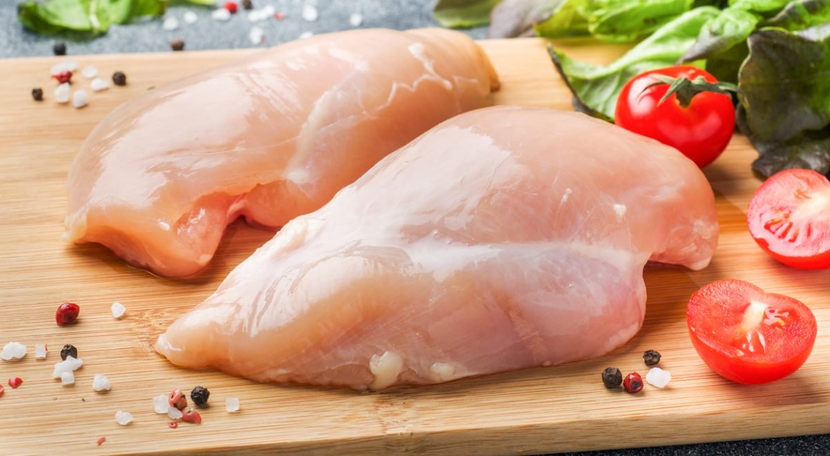 Frango cru - iStock - Imagem ilustra pedaços de frango cru em tábua