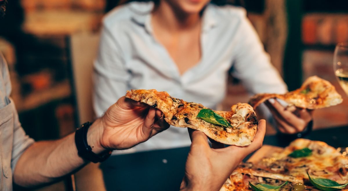 Dejan Dundjerski/IStock
- Imagem de pessoas se servindo com pedaços de pizza