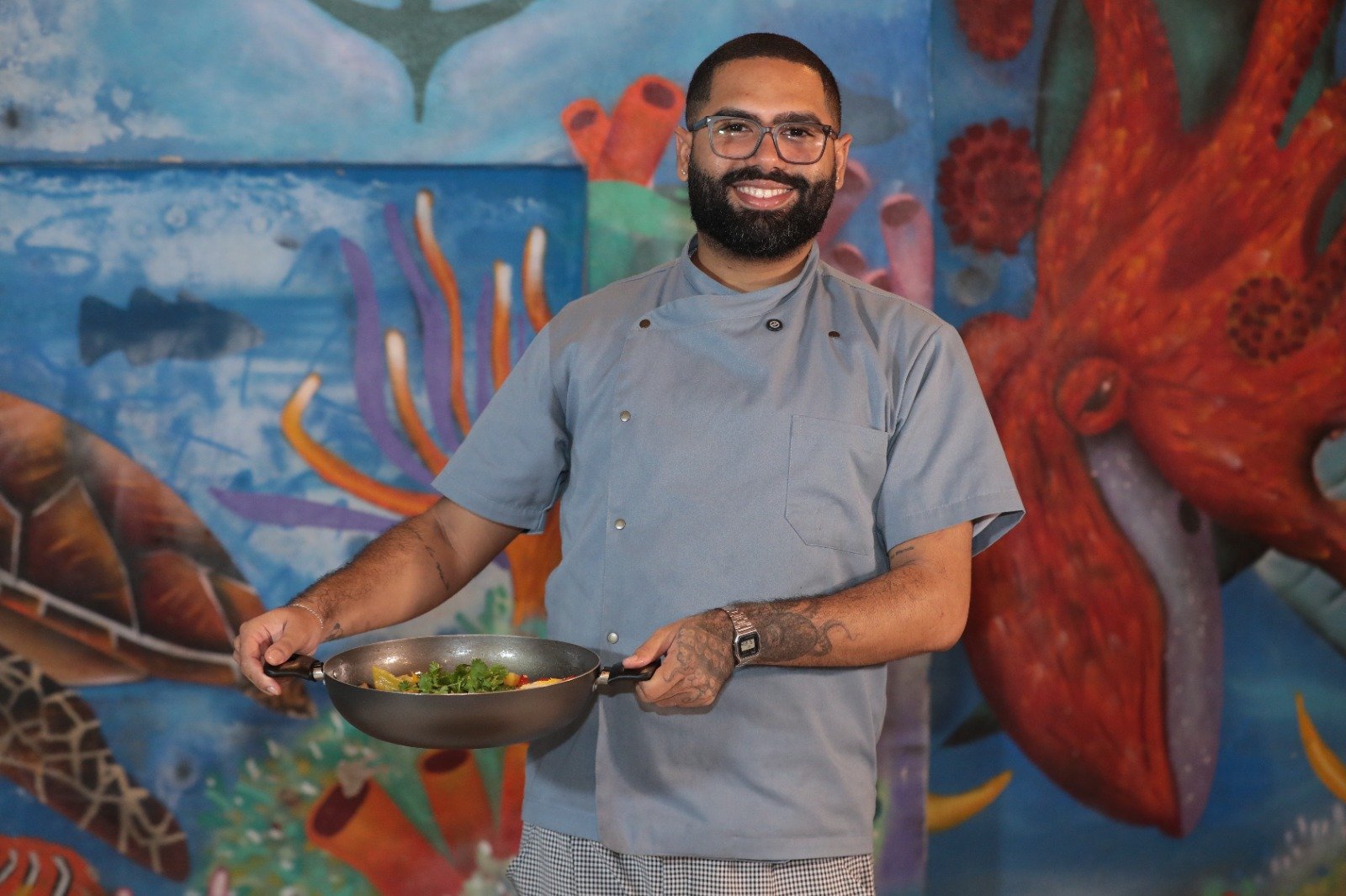 Chef Danilo Vieira segurando um prato de Peixada Pernambucana para o programa Receita da Boa na TV Jornal